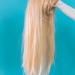 Client browsing salon display to buy hair extensions made from natural human hair.